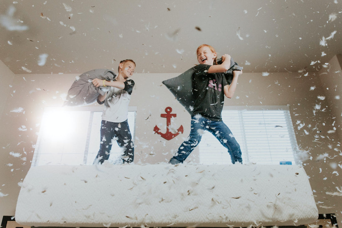 kids having a pillow fight on a bed with feathers flying everywhere