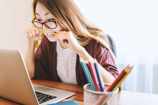 Image of a woman over a computer biting a pencil