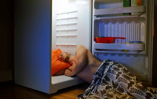 man laying on floor paritally in fridge to cool down