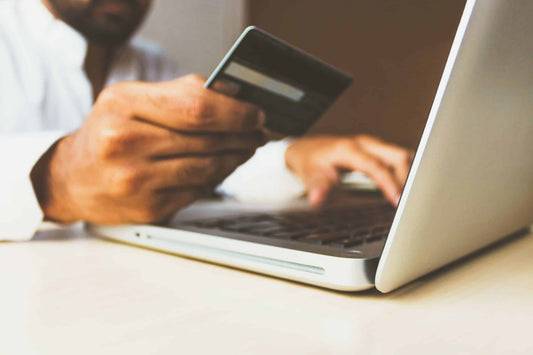 a man holding a credit card ready to shop online on his laptop