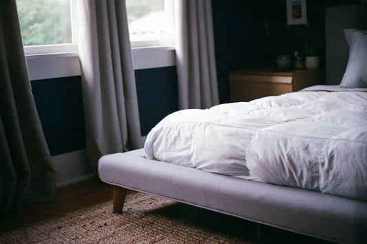 Image of bed with light coming through the windows in a cozy modern bedroom