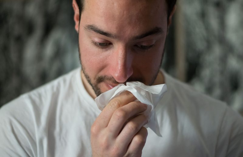 Man wiping face with tissue due to allergies that could be solved from a hypoallergenic mattress